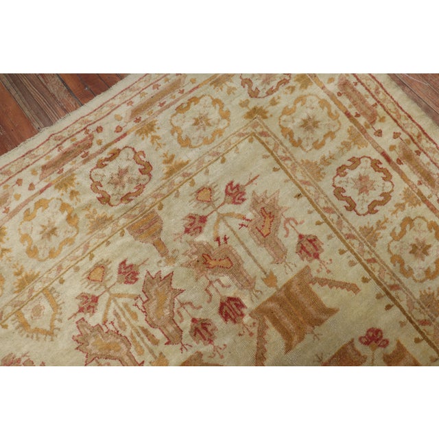 An early 20th-century Turkish Oushak rug with a pictorial bird and small palmette all over design on an ivory field....