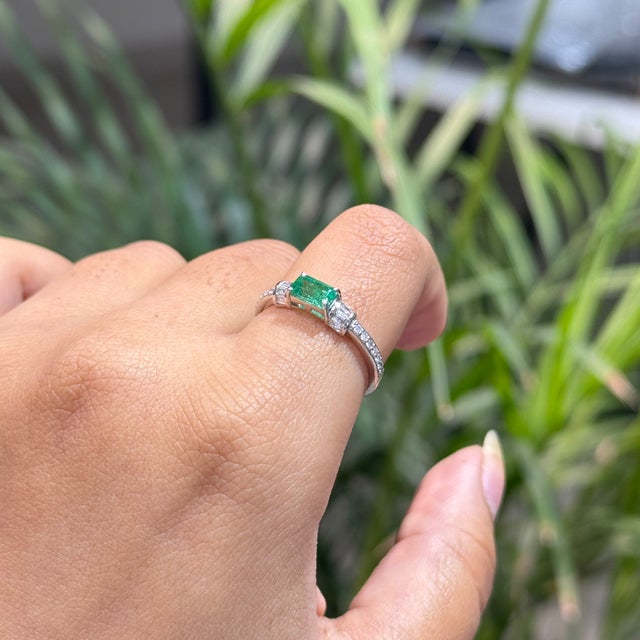This East-West ring features a 0.61 ct natural Zambian octagon emerald, set in 14K white gold. Each measuring 6 × 3.5 mm,...