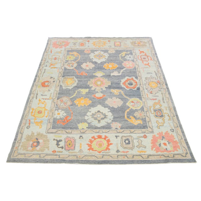 This hand-knotted wool rug is a modern Turkish piece featuring a gray field with a light blue frame and a captivating...