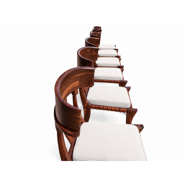 A striking set of eight solid walnut Klismos dining chairs in the style of T.H. Robsjohn-Gibbings. Broad, curved backs,...