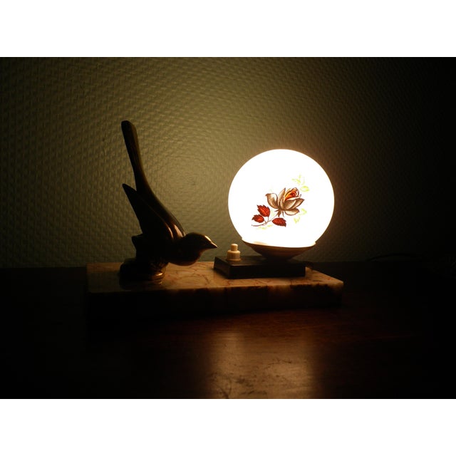 This 1940s Art Deco table lamp stands out from the rest thanks to its white opaline glass shade adorned with two black...