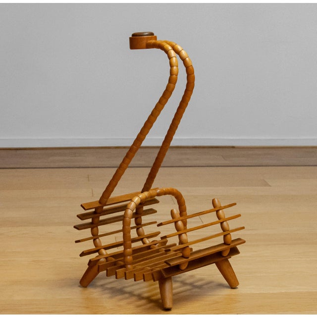 A sculptural 1940s magazine rack crafted from beech, featuring an elegantly curved handle inlaid with oak. The bentwood...