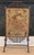 Antique fireplace screen featuring turned faux bamboo wooden frame with warm, aged gilt accents and an inset floral...