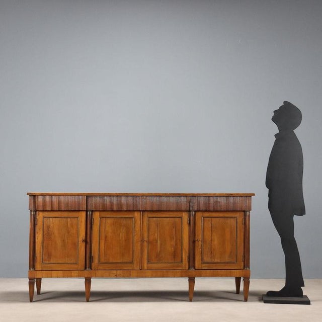 Empire-style walnut sideboard. Four-door paneled front with brass sheet moldings, surmounted by four drawers in the fully...