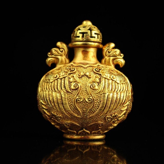 This is a finely crafted gilt copper snuff bottle, featuring intricate engraved (chiseled) decoration throughout. The body...