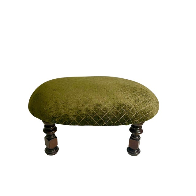 A charming footstool featuring a generously padded seat upholstered in rich olive or moss green fabric with subtle diamond...