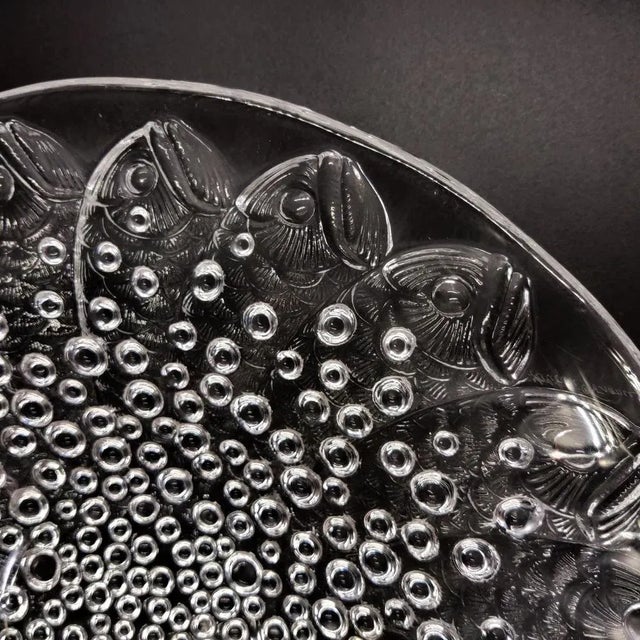 An iconic design by René Lalique: Fishes and small bubbles form an exciting whirl on this heavy glass platter. A true...