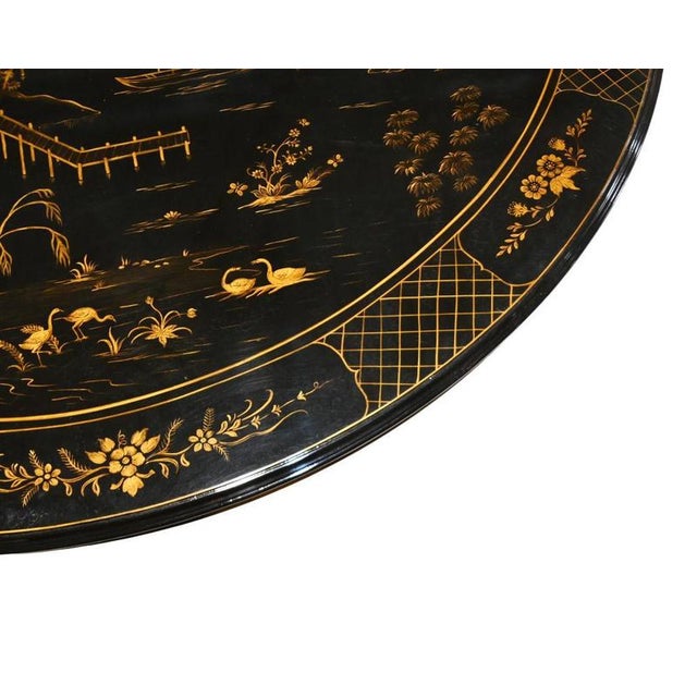 Striking Regency style dining table with a black lacquered finish Circular top richly decorated in gilt with an extensive...