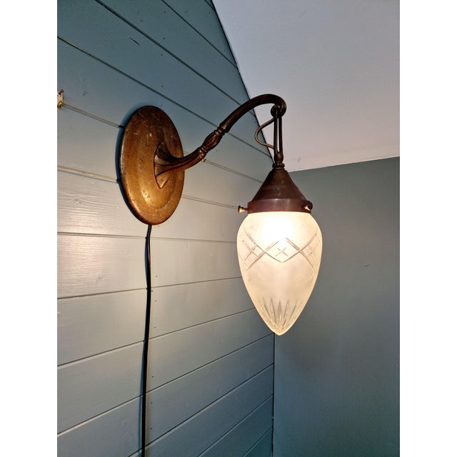 Art Deco bronze wall sconce with a satin-finished crystal globe, cut to a point, circa 1910-20. The sconce has been...
