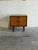 This architectural bedside chest features a compact box frame elevated by slender tapered legs. Two smooth pull-out...