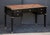 An elegant double-sided French writing desk or table of ebonized mahogany with gilt accents in the Louis XVI style....