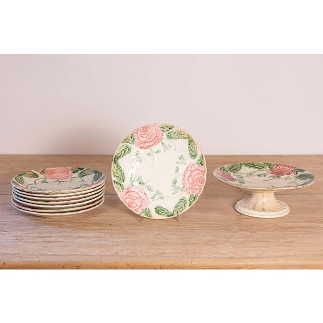 A French majolica compote and seven plates from the 19th century, with roses and foliage, priced and sold individually....