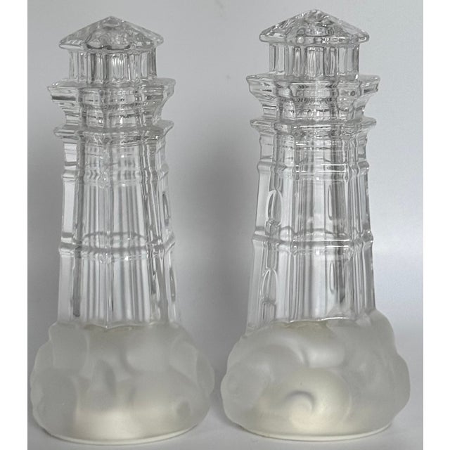 Here is a pair of crystal lighthouse motif salt and pepper shakers produced by Lenox in the 1990's. Frosted "waves" lap...