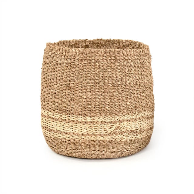 Cylindrical woven handmade seagrasss basket with beige stripes.