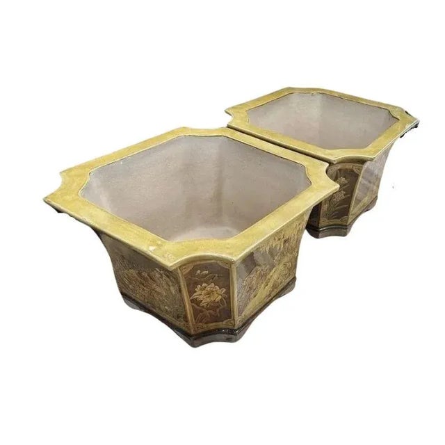 A pair of large glazed ceramic planters with an Asian scene. The vintage terracotta planters are ochre and brown in color...