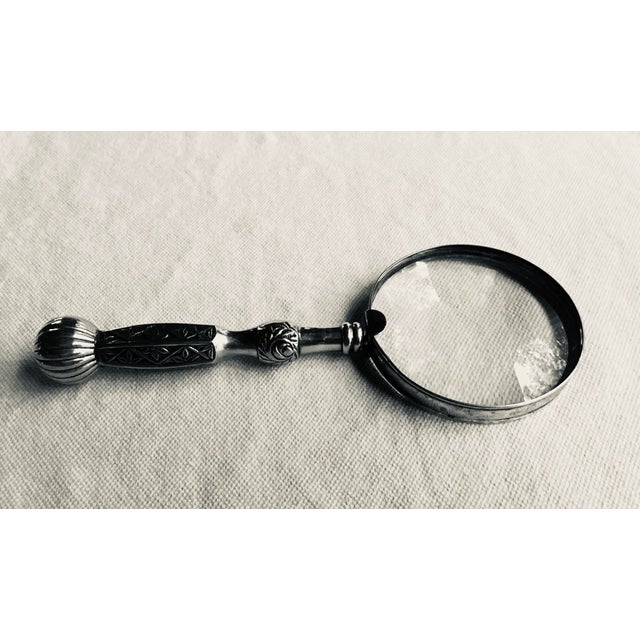 …A substantial antique magnifying glass from the Aesthetic Movement, its silverplate handle and frame cast with the...