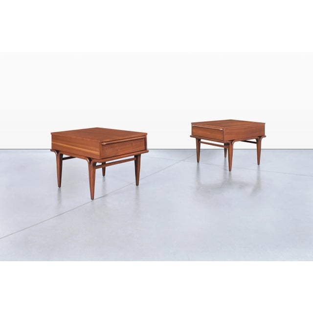 Crafted in the United States during the 1960s, this pair of mid-century modern walnut side tables showcases the clean...