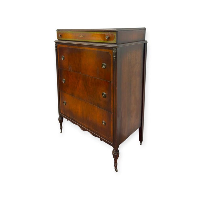 This vintage wooden tallboy dresser features a deep warm stain with visible wood grain panels, four total stacked drawers,...