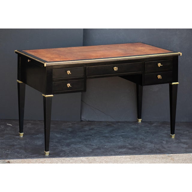 An elegant double-sided French writing desk or table of ebonized mahogany with gilt accents in the Louis XVI style....