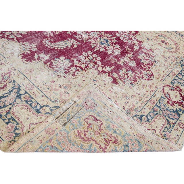 Beautiful vintage distressed medallion hand-knotted wool rug with a red field. This rug has ivory and blue accents in a...