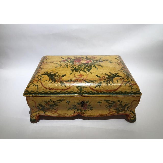 This is an elegant lacquered and shaped wooden box, with fine and polychrome flowers decoration on yellow background. In...