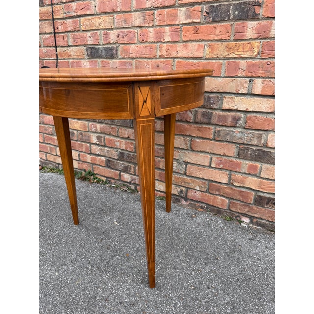 This is a 19th Century Federal-style round table made of satinwood and mahogany, featuring lovely inlaid marquetry details...