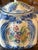 Glazed ceramic floral teapot with decorative lid and blue accents.