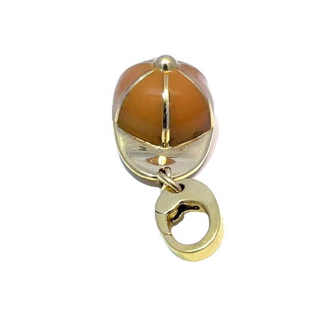 Authentic Gucci hat pendant crafted in solid 18k yellow gold with glossy orange enamel detailing. This charming 6.1g piece...