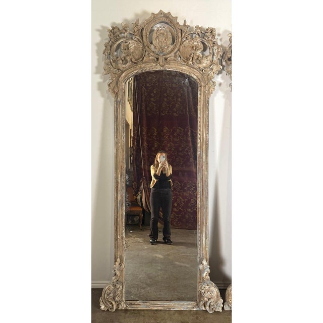 A rare and monumental pair of Italian Baroque pier mirrors, hand-carved in solid wood and retaining their original mirror...