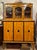 This tall vitrine sideboard combines a warm, highly figured birch veneer with ebonised mouldings and striking circular...