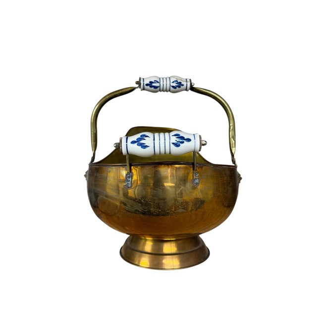 A Brass and porcelain fireplace bin for coal or firewood. Polished with a circular foot, lion accents and cobalt painted...