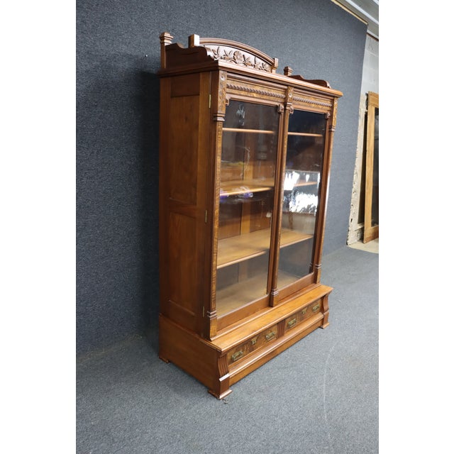 Victorian Eastlake bookcase in walnut with striking burl wood accents. The upper case features two glass doors opening to...