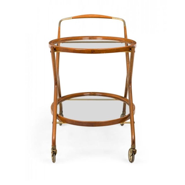Italian Mid-Century oval form serving trolley / tea cart with teak frame, two inset glass shelves, and a brass handle and...