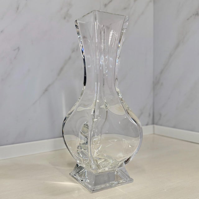 Baccarat’s “Lotus” vase rises like a stem from its own pedestal. Clear French lead crystal, square at the foot and gently...