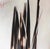 Quills presents a striking arrangement of elongated, dark forms that evoke the essence of quills against a soft, muted...