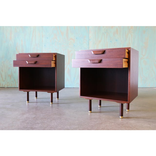 A pair of nightstands designed by Harvey Probber c. 1950s. Rich mahogany cases with two thin draers and open cubby below...