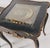 A jewel-box end table with a beveled-glass window revealing an ornate gilt and silvered wheel medallion. Description:...