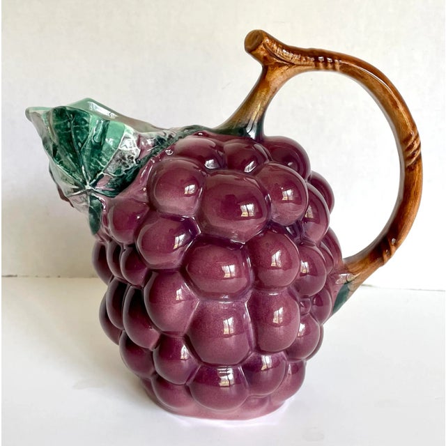 Here is a charming pitcher that resembles a bundle of purple grapes with a brown, stem handle and leafy spout! It is...