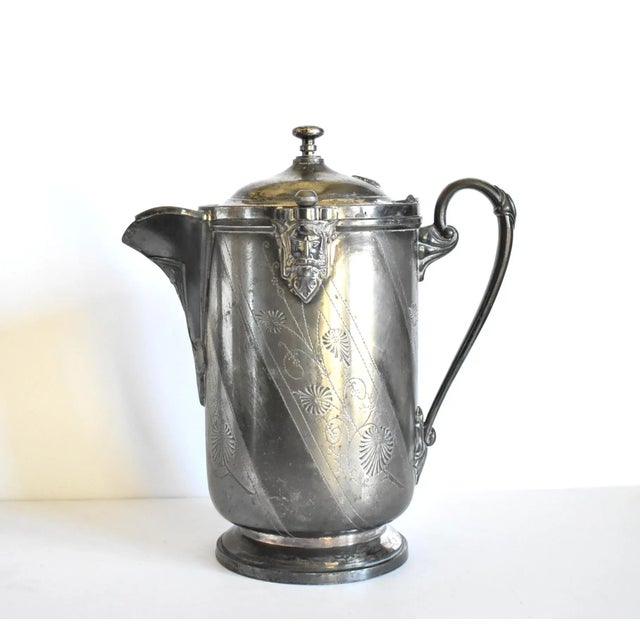 An antique, Victorian, c.1870s Aesthetic Era lidded water pitcher, with bearded faces on the sides and chased foliate...