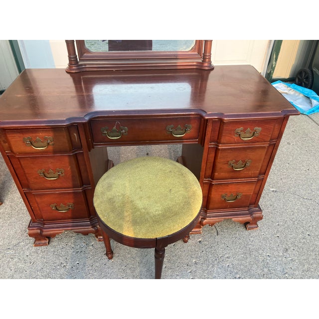 This vanity with swinging mirror and stool comes from the mid 20th century. It is a mahogany chippendale style vanity....