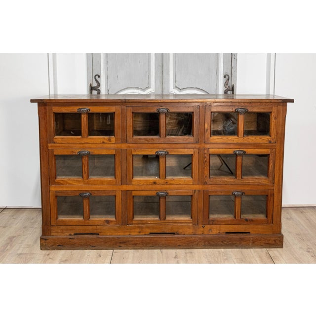 An Italian walnut pastaia shop cabinet from the 20th century with nine drawers, glass panels and iron hardware. Crafted in...