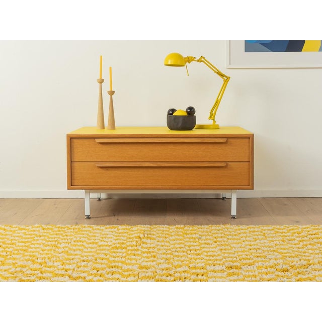 Classic chest of drawers from the 1960s. Body in oak veneer with two drawers and new square steel feet in white. The top...