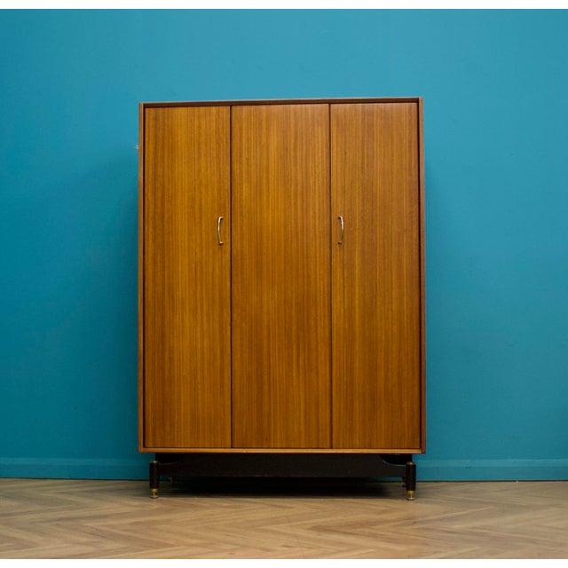 A mid century three door Tola and Black wardrobe from G Plan (EGomme) Featuring a bi fold door and a rail the full width...