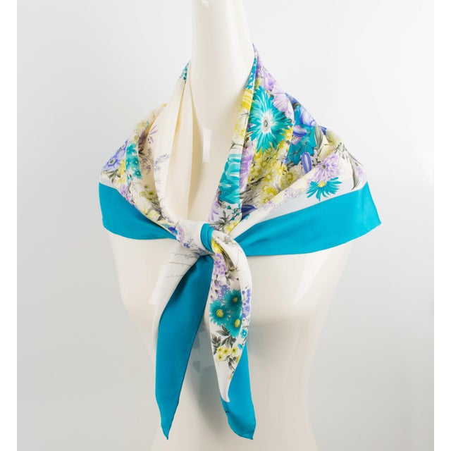 This exquisite silk scarf by Christian Dior features a floral design print in blue, lavender, and yellow colors. Christian...