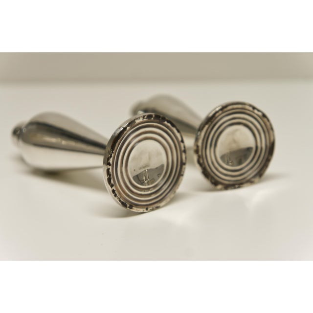 A pair of weighted sterling silver salt and pepper shakers with screw-on lids, likely dating from the late 19th to early...