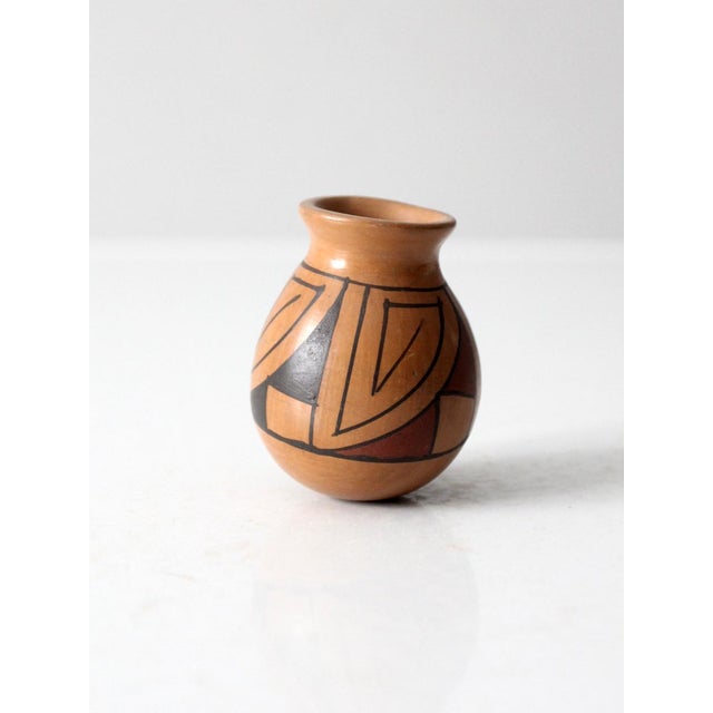 A vintage Southwestern-style mini studio pottery vase with a warm brown glaze and hand-drawn geometric banding in deep...