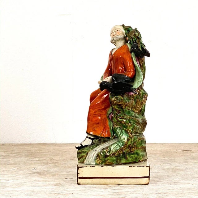 An early 19th Century English Staffordshire of Elijah and the Raven, circa 1800. This figure of Elijah is dressed in a...