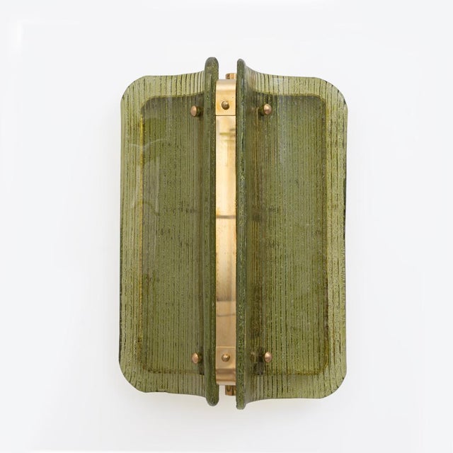 An elegant pair of italian wall sconces made of curved and fluted murano glass panels in a refined shade of green. The...