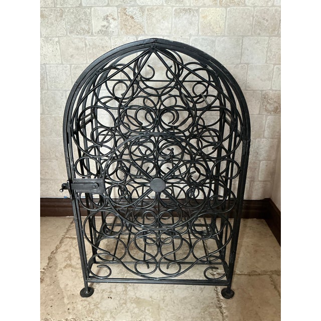 This vintage wrought‑iron wine rack features beautifully curved scrollwork, circular bottle cradles, and a decorative...
