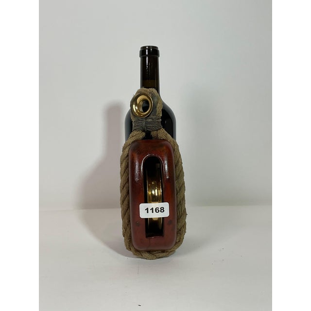 Varnished wood shell ship’s pulley block with rope stropping and brass grommet. The brass pulley has been meticulously...